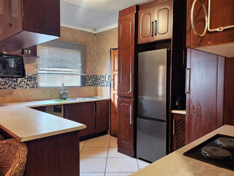 A functional kitchen featuring dark wood cabinetry, laminate countertops, tiled backsplash, and built-in cooking appliances, offering a classic layout with potential for modern updates.