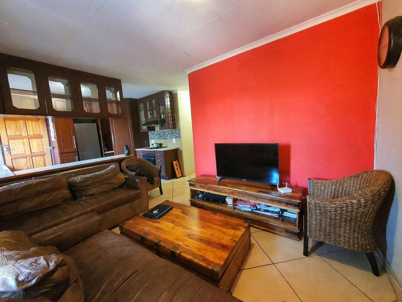 Open plan living area featuring tiled floors and a connected kitchen with built-in cabinetry and appliances.
