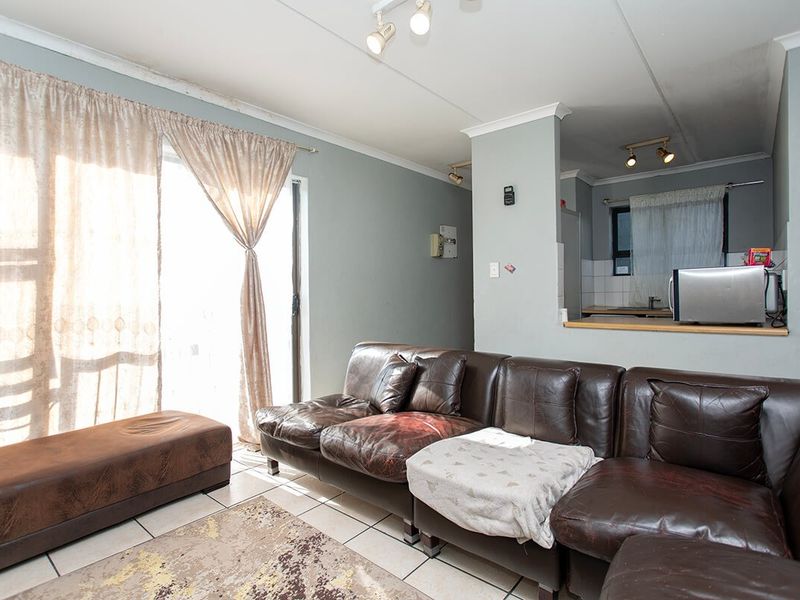 Open plan living area featuring tiled floors, a sliding door to the exterior, and a convenient kitchen pass-through with track lighting.