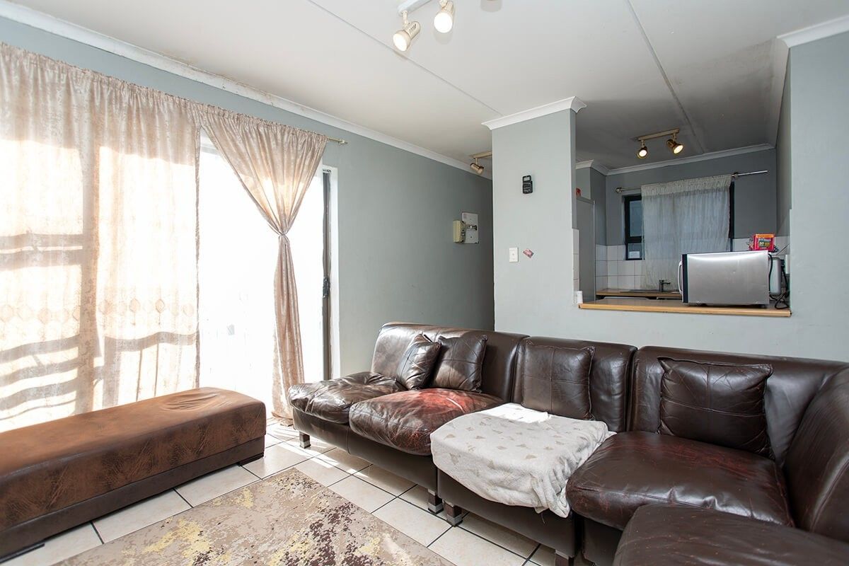Open plan living area featuring tiled floors, a sliding door to the exterior, and a convenient kitchen pass-through with track lighting.