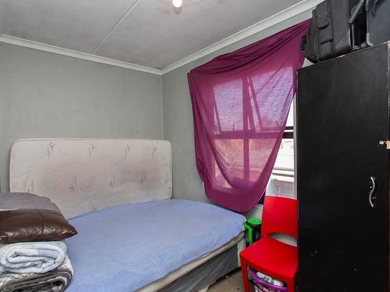 A compact bedroom featuring standard finishes, requiring cosmetic updates to the walls and ceiling to improve the overall aesthetic.
