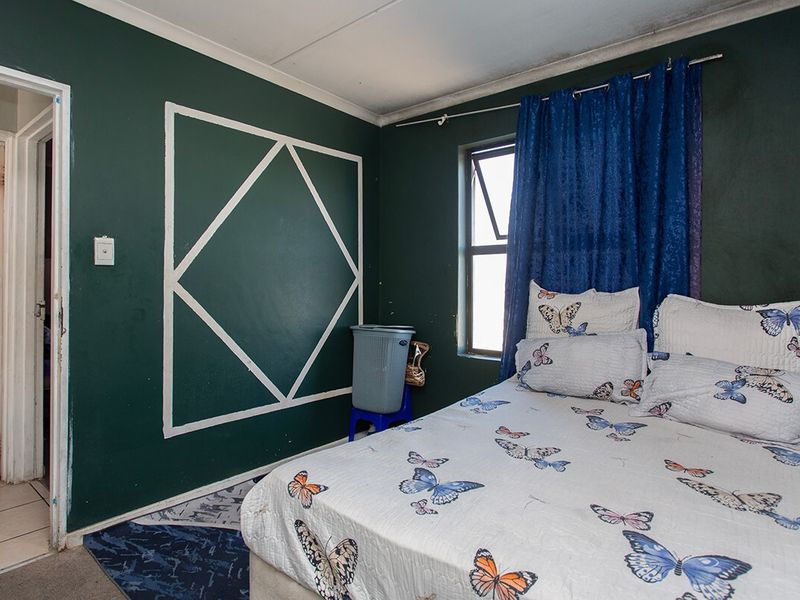 A bedroom featuring dark green painted walls with decorative trim and a casement window, requiring some ceiling maintenance and cosmetic updates.