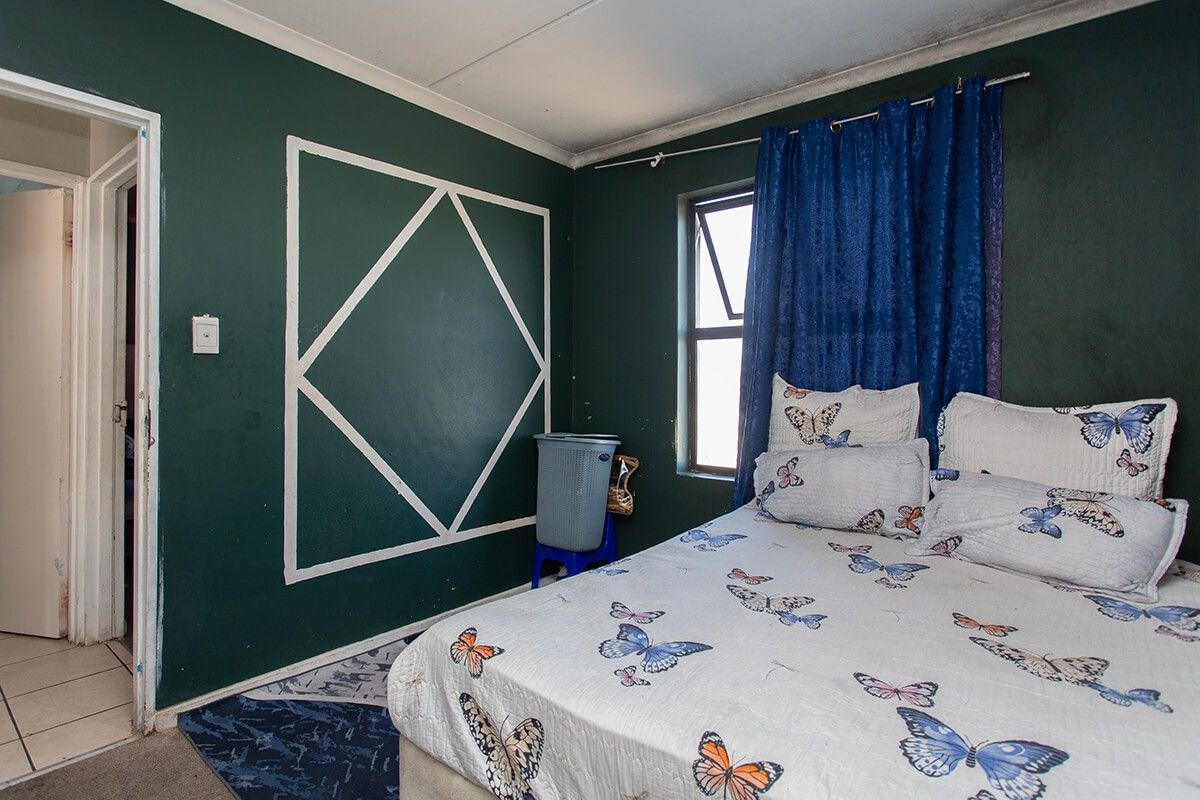 A bedroom featuring dark green painted walls with decorative trim and a casement window, requiring some ceiling maintenance and cosmetic updates.