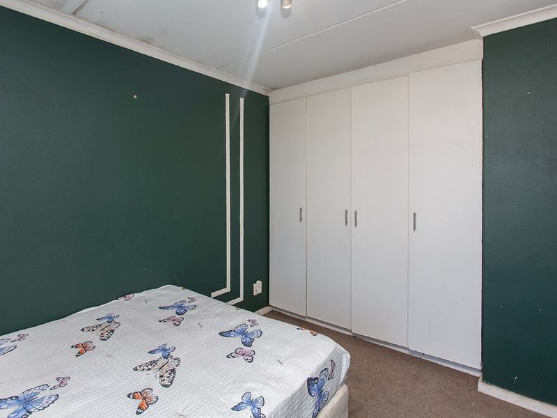 Bedroom featuring built-in cupboards and carpeted flooring, requiring ceiling repairs and cosmetic updates to improve the overall condition.