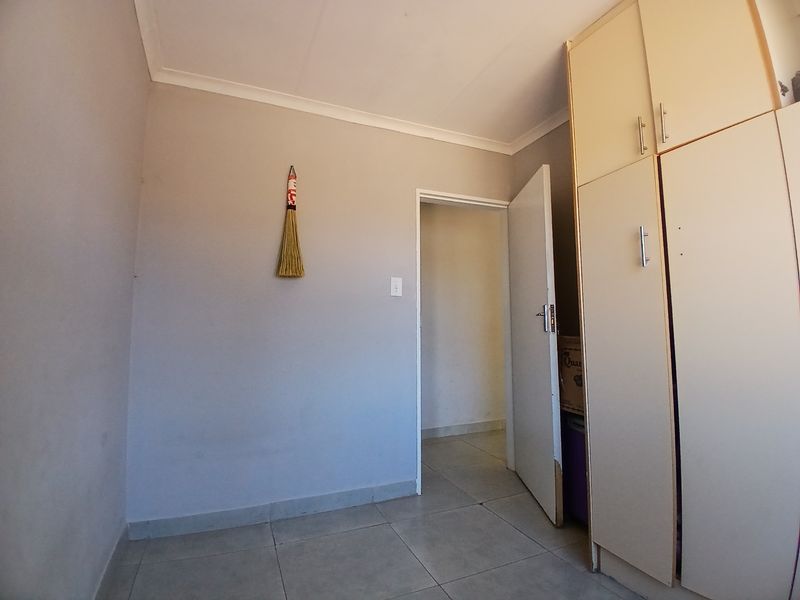 A vacant bedroom featuring built-in cupboards, tiled flooring, and neutral wall finishes, offering a blank canvas for personalization.