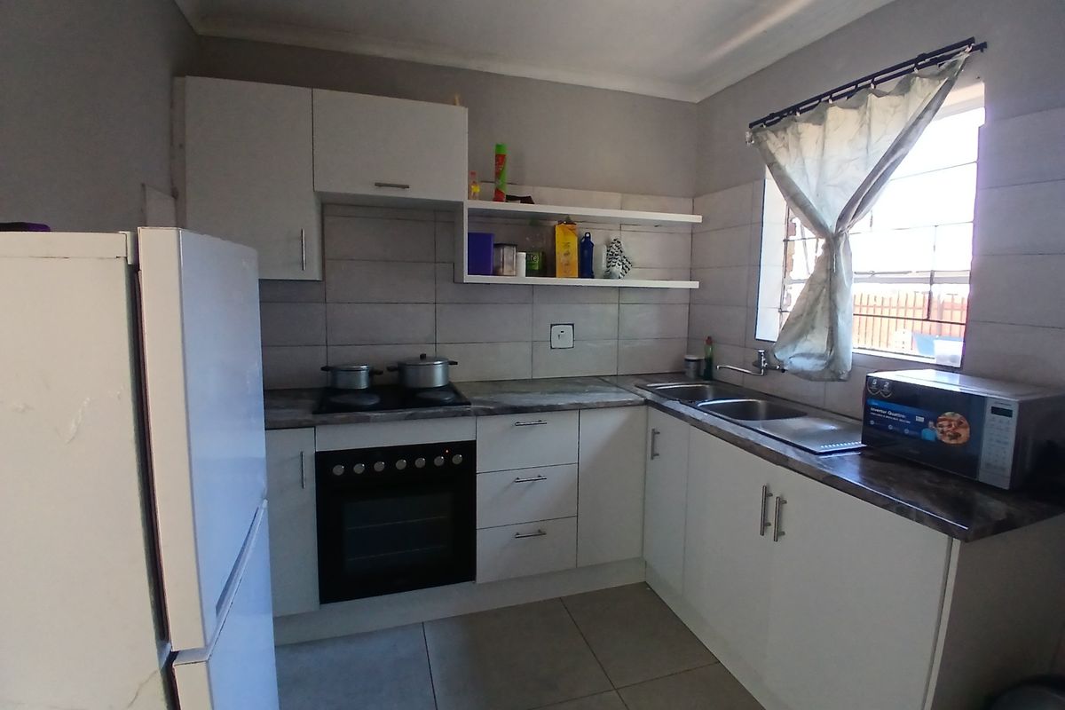 A functional kitchen featuring white built-in cabinetry, laminate countertops, a built-in oven with hob, and a double sink with tiled backsplash.