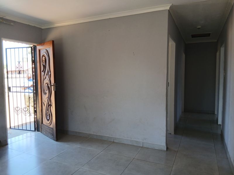 Entrance area featuring a decorative wooden front door, security gate, and neutral tiled flooring leading into a hallway.