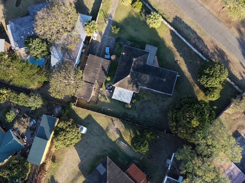 Aerial view of the residential property showing the main dwelling, roof structure, driveway, and surrounding garden area.