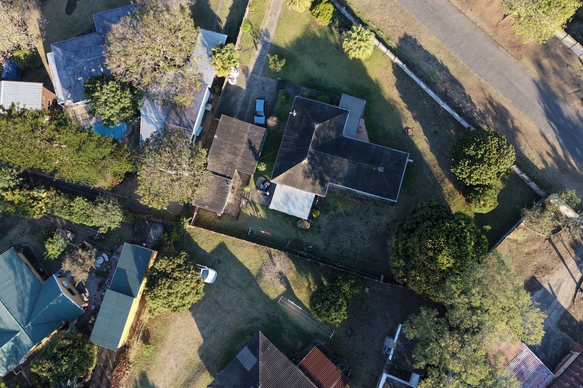 Aerial view of the residential property showing the main dwelling, roof structure, driveway, and surrounding garden area.