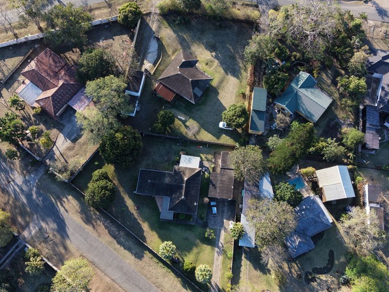 An aerial view of a residential neighborhood showcasing multiple properties with tiled roofs, swimming pools, and established garden areas.