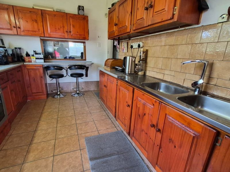 A functional kitchen featuring traditional wooden cabinetry, tiled backsplash, built-in oven, and a convenient breakfast counter area.