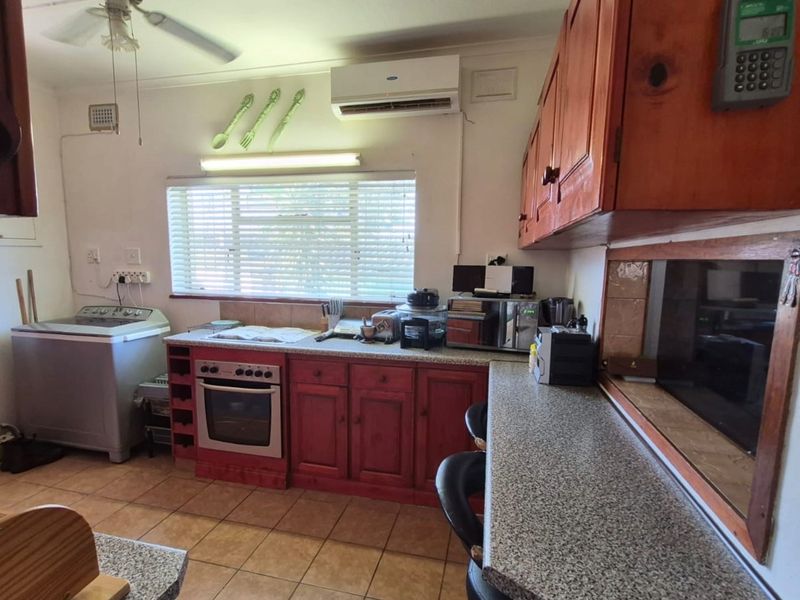 A functional kitchen featuring wooden cabinetry, granite countertops, built-in oven, and a split-system air conditioner, with tiled flooring throughout.