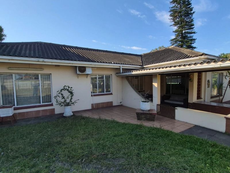 Rear view of the house featuring a tiled patio area, concrete roof tiles, and an installed air conditioning unit.