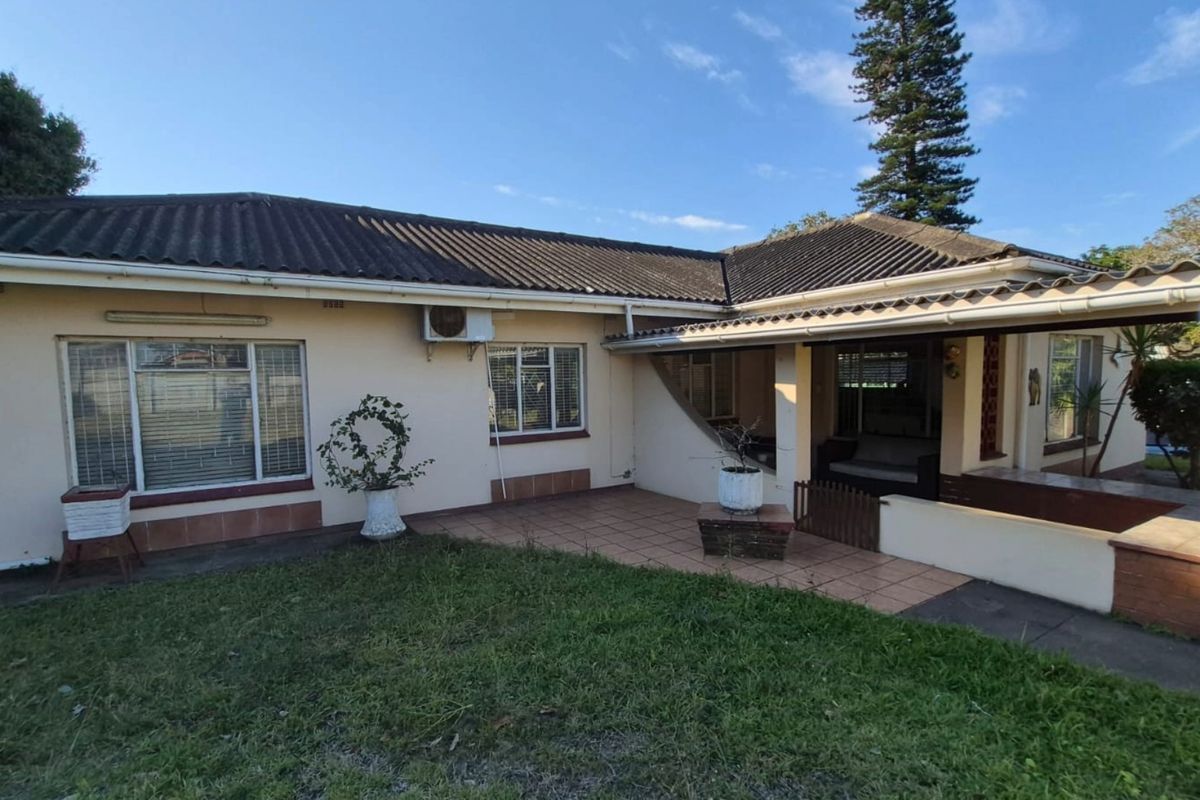 Rear view of the house featuring a tiled patio area, concrete roof tiles, and an installed air conditioning unit.