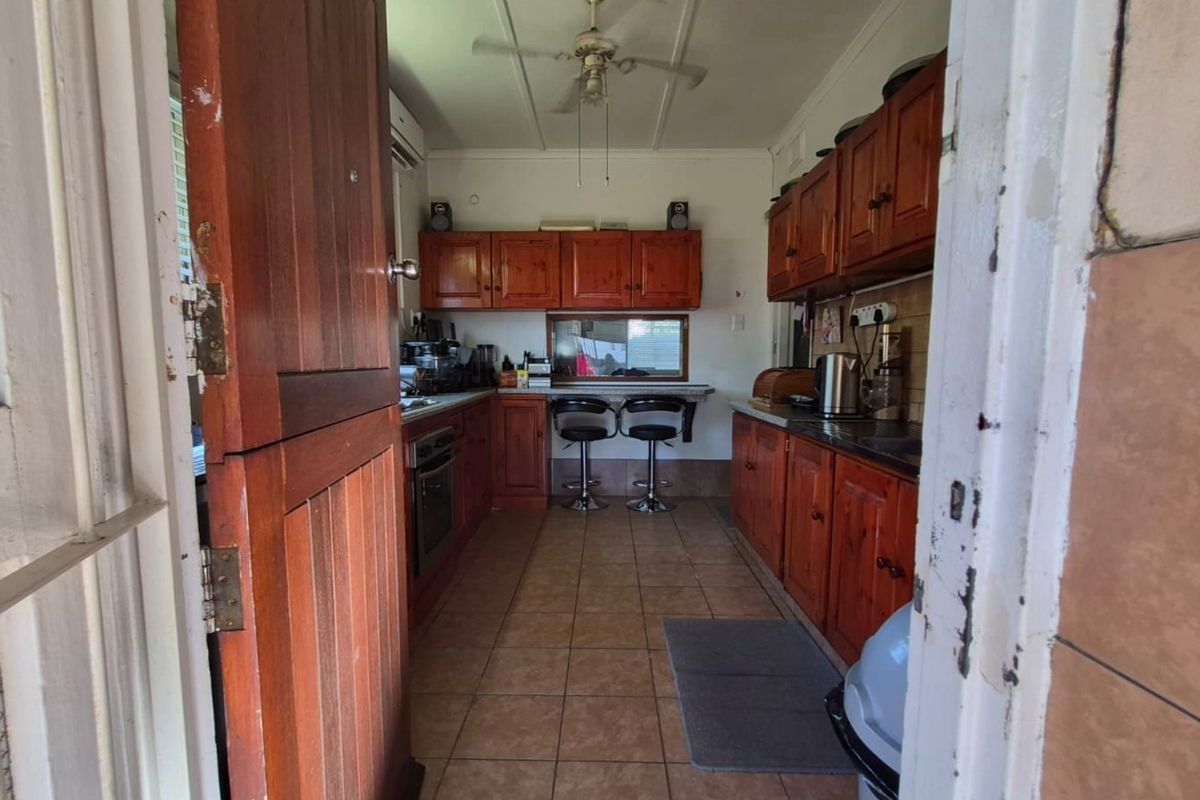 A functional kitchen featuring traditional wooden cabinetry, tiled flooring, and a built-in oven, offering a classic layout with potential for modern updates.