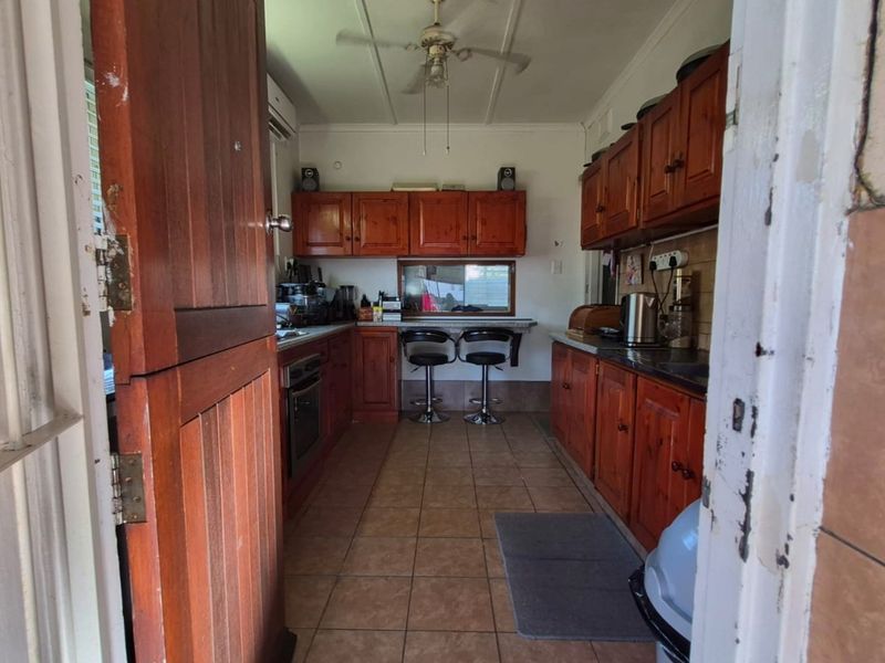 A functional kitchen featuring traditional wooden cabinetry, tiled flooring, and a built-in oven, offering a classic layout with potential for modern updates.
