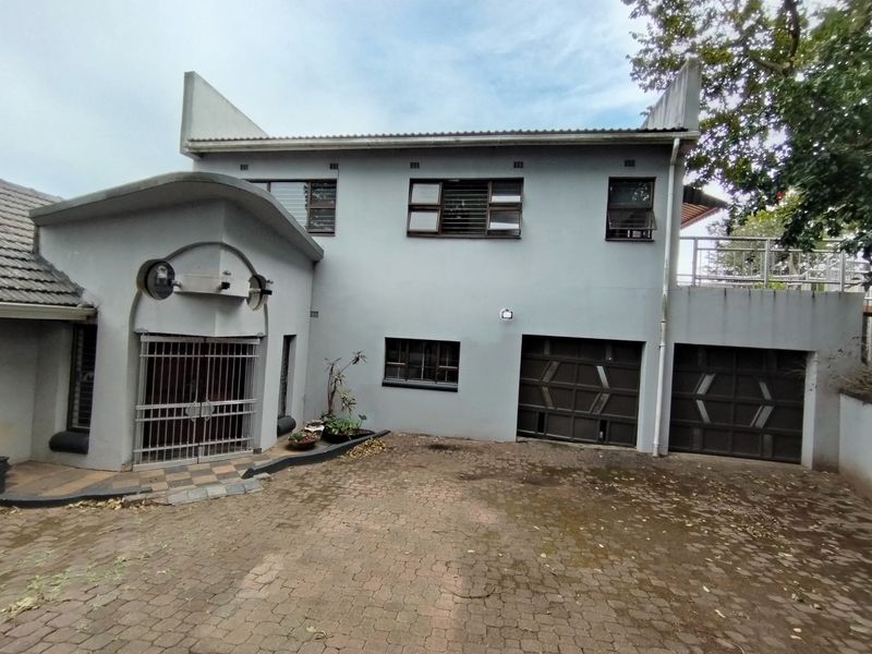 Front elevation of a two-story house featuring a paved driveway, double garage, and secure entrance gate.