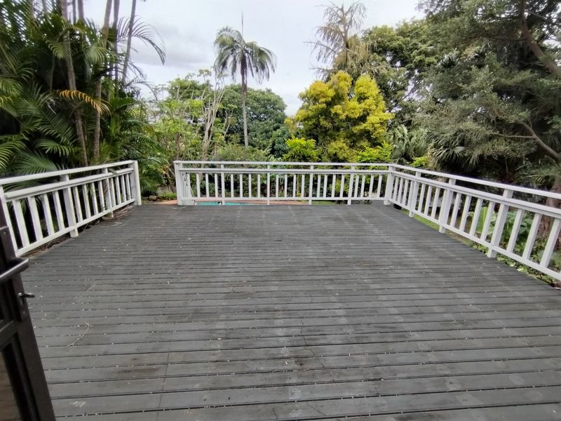 An elevated timber deck featuring a white balustrade, overlooking a lush garden area, providing an ideal space for outdoor relaxation.