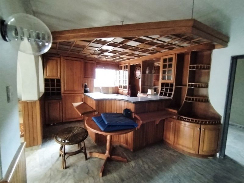 A dedicated bar area featuring extensive built-in wooden cabinetry, a coffered ceiling, and stone flooring, offering a classic entertainment space.