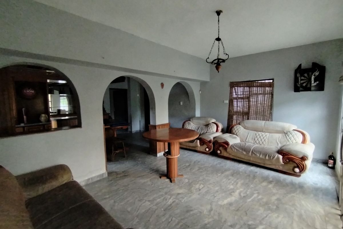 Spacious living area featuring distinctive arched wall openings, marble-look flooring, and a built-in bar counter, offering a versatile layout for relaxation and entertaining.