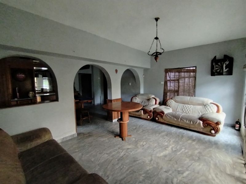 Spacious living area featuring distinctive arched wall openings, marble-look flooring, and a built-in bar counter, offering a versatile layout for relaxation and entertaining.