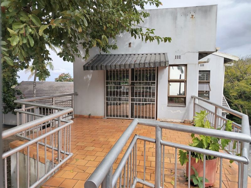 An elevated balcony featuring tiled flooring, metal safety railings, and a security gate, providing an outdoor space with potential for refurbishment.