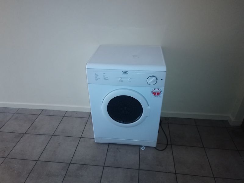 A functional laundry area featuring tiled flooring and a dedicated space for a washing machine.