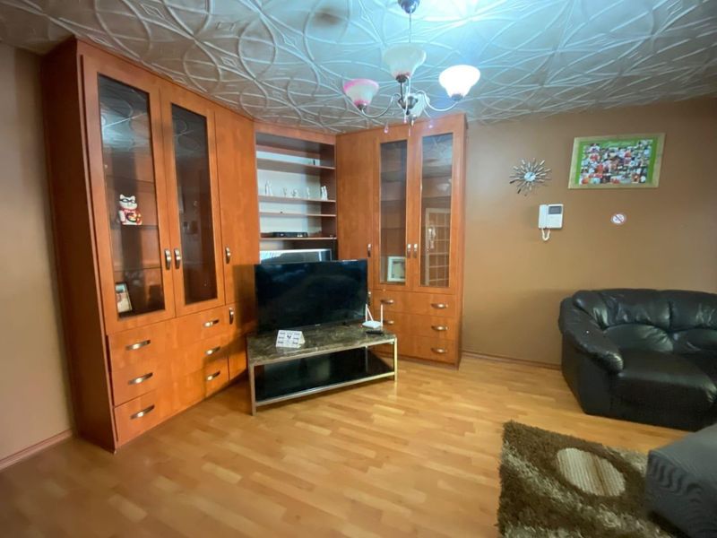 Living room featuring extensive built-in wooden cabinetry, laminate flooring, and decorative ceiling tiles, providing ample storage and a traditional aesthetic.