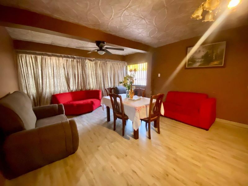 Open plan living and dining area featuring laminate flooring, a ceiling fan, and textured ceiling finishes.