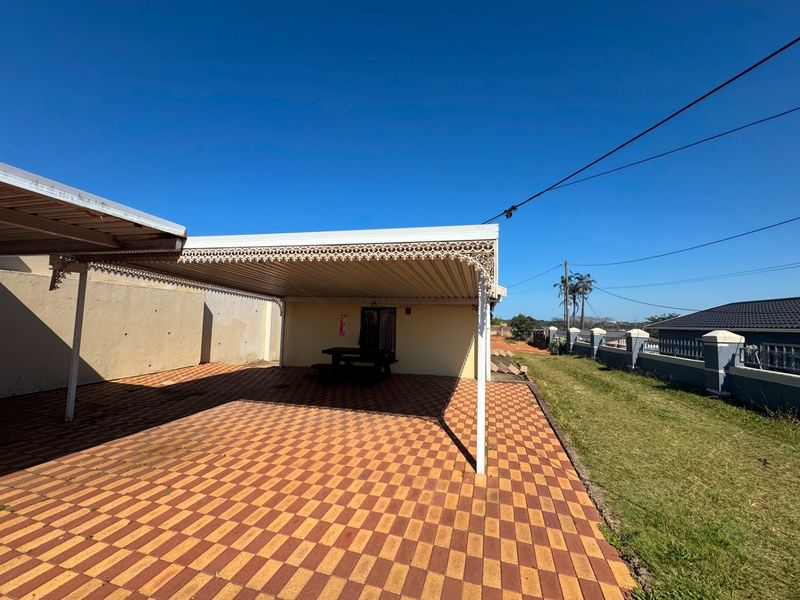 A covered outdoor patio area featuring paved flooring and decorative metal trim, providing a functional space for outdoor activities.