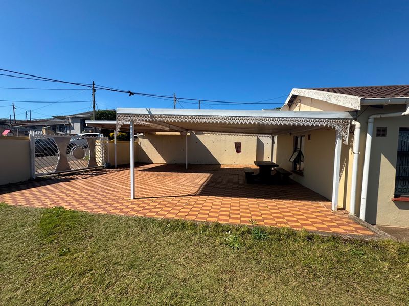 A spacious covered patio area featuring paved flooring and decorative metal detailing, providing a functional outdoor space for relaxation or entertainment.