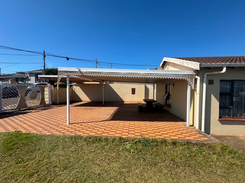 A spacious covered patio area featuring decorative metal detailing, tiled flooring, and direct access to the property exterior.