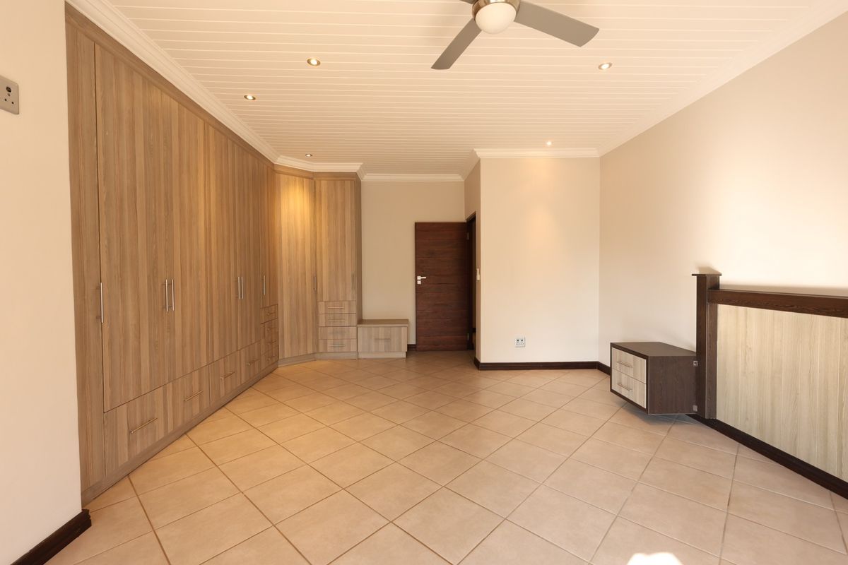 Spacious bedroom featuring extensive built-in wooden cabinetry, tiled flooring, a ceiling fan, and recessed lighting, offering a clean and functional layout.