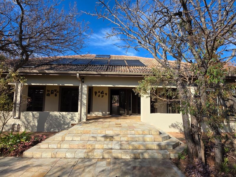 Front elevation of a single-story residence featuring a tiled roof with integrated solar panels and a stone-paved entrance staircase.