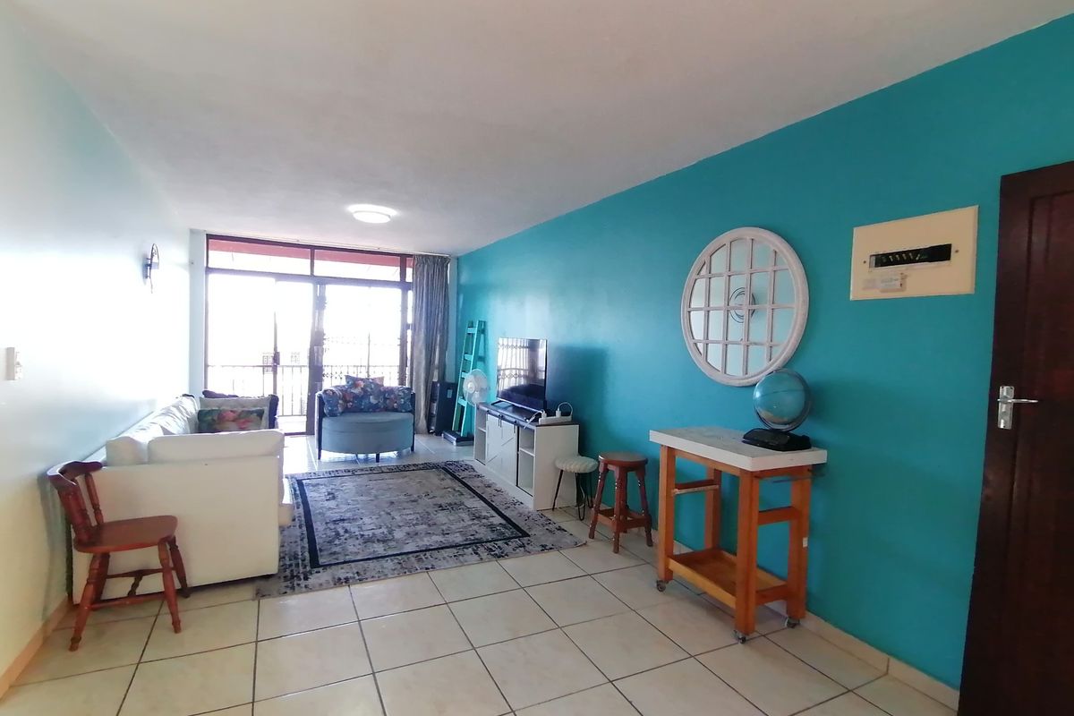 A living room featuring tiled flooring and a large sliding glass door providing access to an outdoor area.