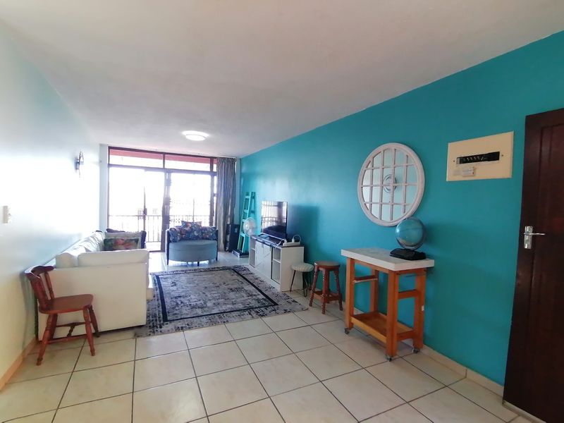 A living room featuring tiled flooring and a large sliding glass door providing access to an outdoor area.
