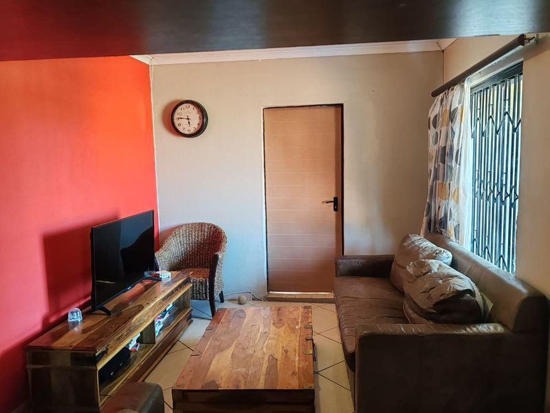 A living room featuring tiled flooring, a security gate on the window, and a bold accent wall.