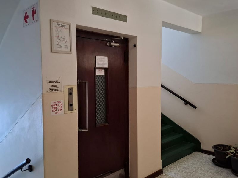 Communal apartment building hallway featuring an elevator access point and a staircase with a handrail.
