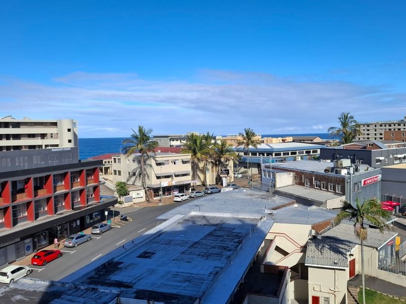 An elevated urban view overlooking the surrounding neighborhood, street infrastructure, and coastal buildings with a glimpse of the ocean in the distance.
