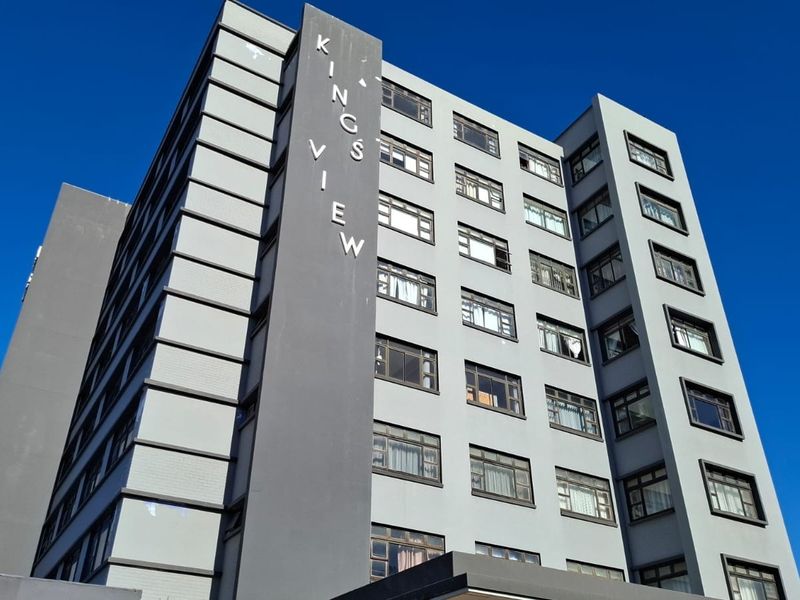 Low angle view of the Kings View apartment building facade featuring grey exterior paint and multiple rows of casement windows.