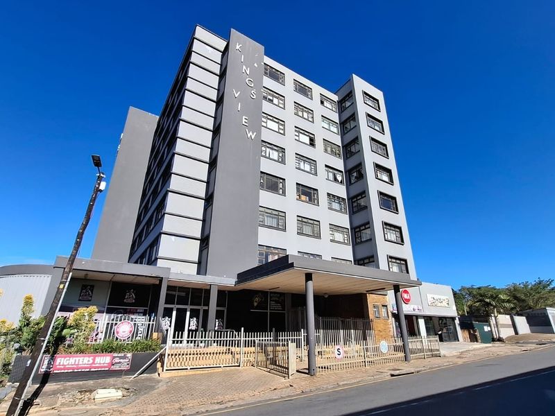 Exterior view of the Kings View apartment building, featuring a multi-story facade, covered entrance canopy, and secure perimeter fencing.