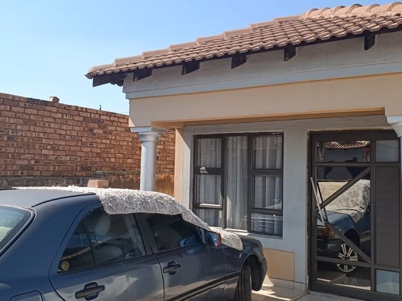 Front elevation of a single-story house featuring a tiled roof, concrete columns, and aluminium window frames with a security gate entrance.