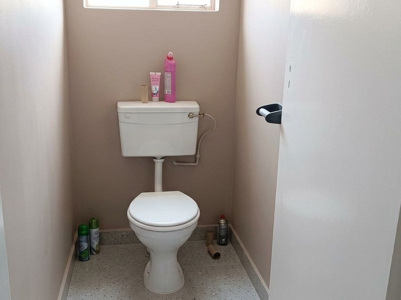 A compact separate toilet room featuring a standard white ceramic toilet suite and a wall-mounted toilet roll holder.