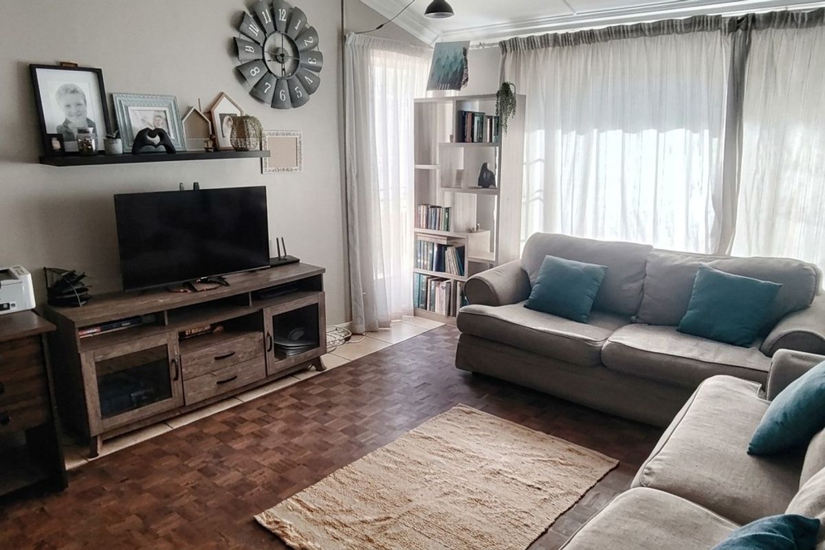 A comfortable living room featuring parquet flooring and large sliding glass doors that provide natural light.