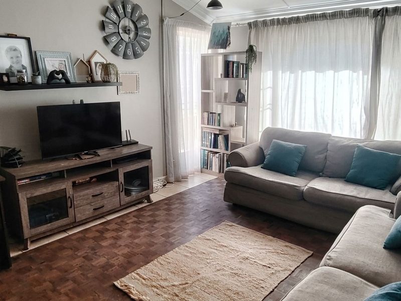A comfortable living room featuring parquet flooring and large sliding glass doors that provide natural light.