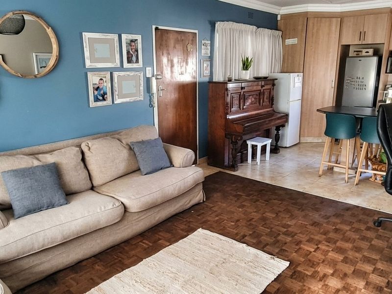 Open-plan living area featuring parquet flooring, integrated kitchen cabinetry, and a functional layout connecting the lounge and kitchen space.