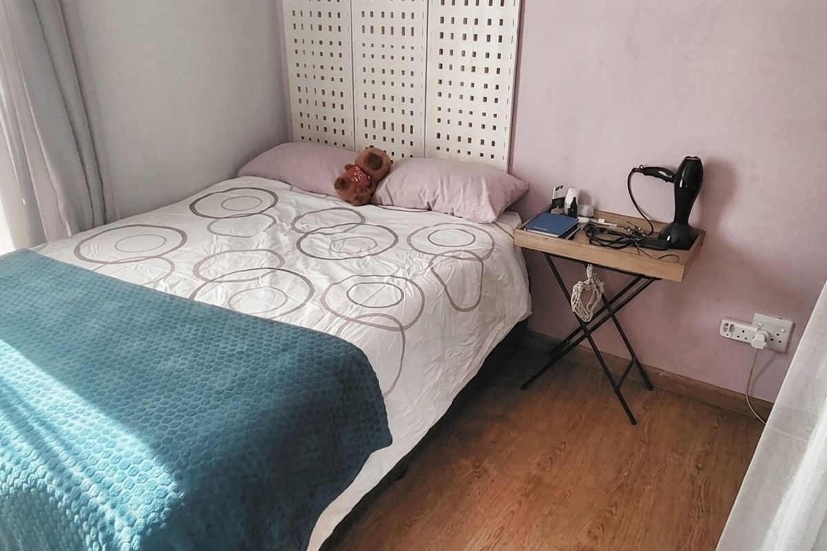 A compact bedroom featuring laminate flooring and natural light, providing a functional space for rest.