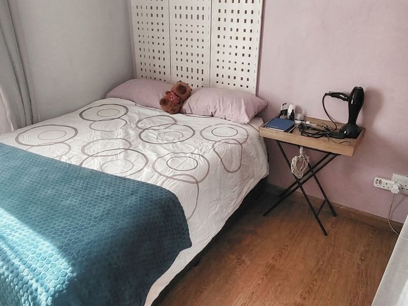 A compact bedroom featuring laminate flooring and natural light, providing a functional space for rest.