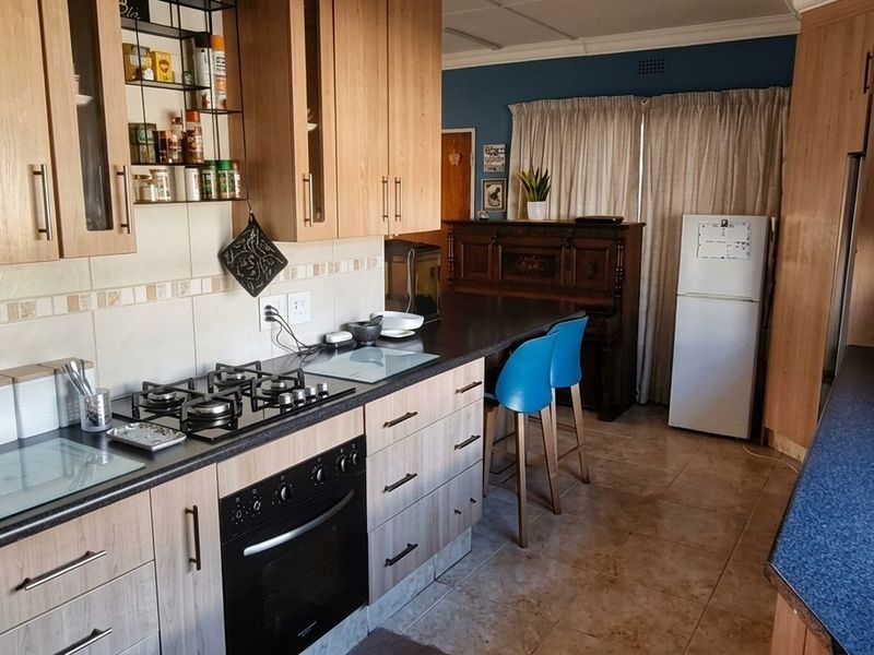 A functional kitchen featuring wood-finish cabinetry, a gas hob, built-in oven, and tiled backsplash with ample counter space.