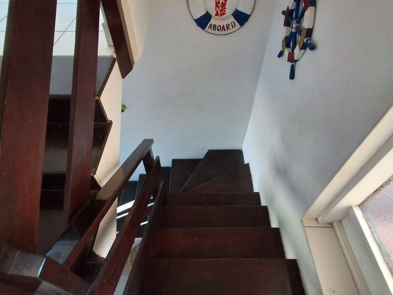 A view looking down a wooden staircase with a matching timber balustrade, featuring tiled flooring at the base.